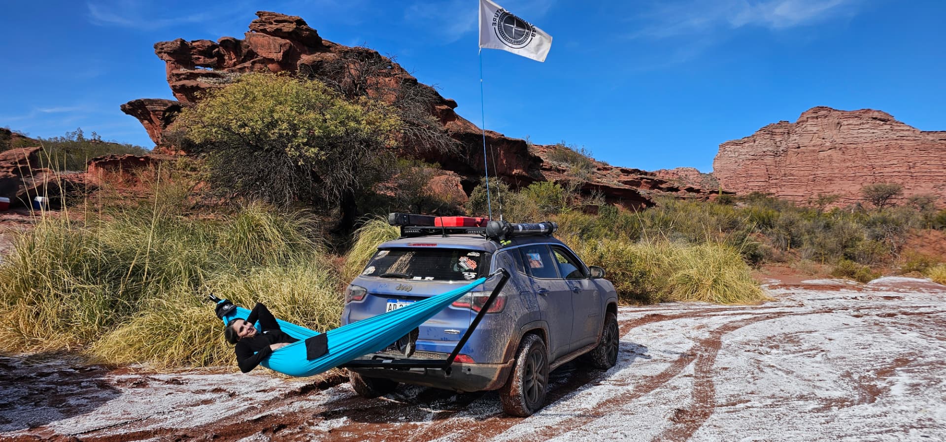 Vista amplia de la 4x4 con hamaca y bandera en campo abierto