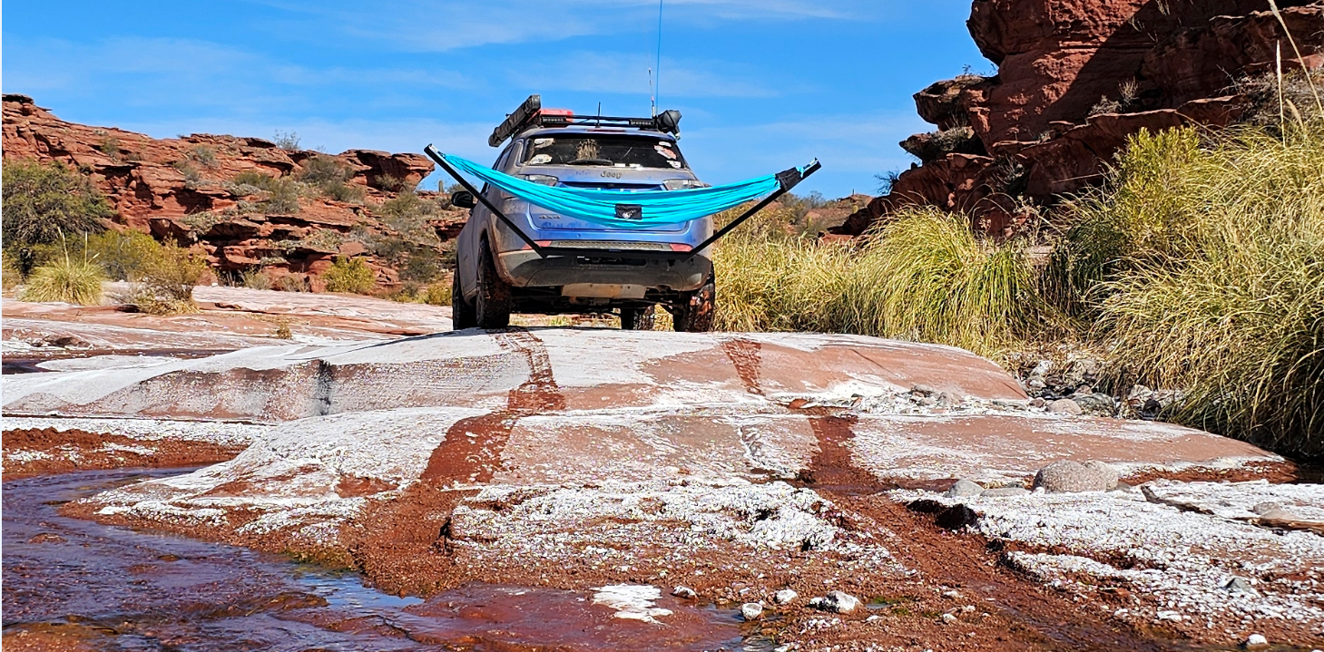 Hamaca turquesa montada en la parte trasera de una 4x4 en un paisaje desértico