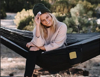Mujer sonriente descansando en una hamaca de camping al aire libre